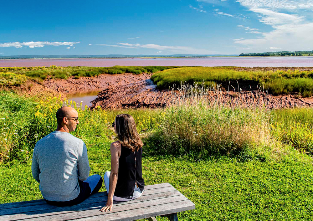 A couple sitting on a picnic table in front of the Shubenacadie River.