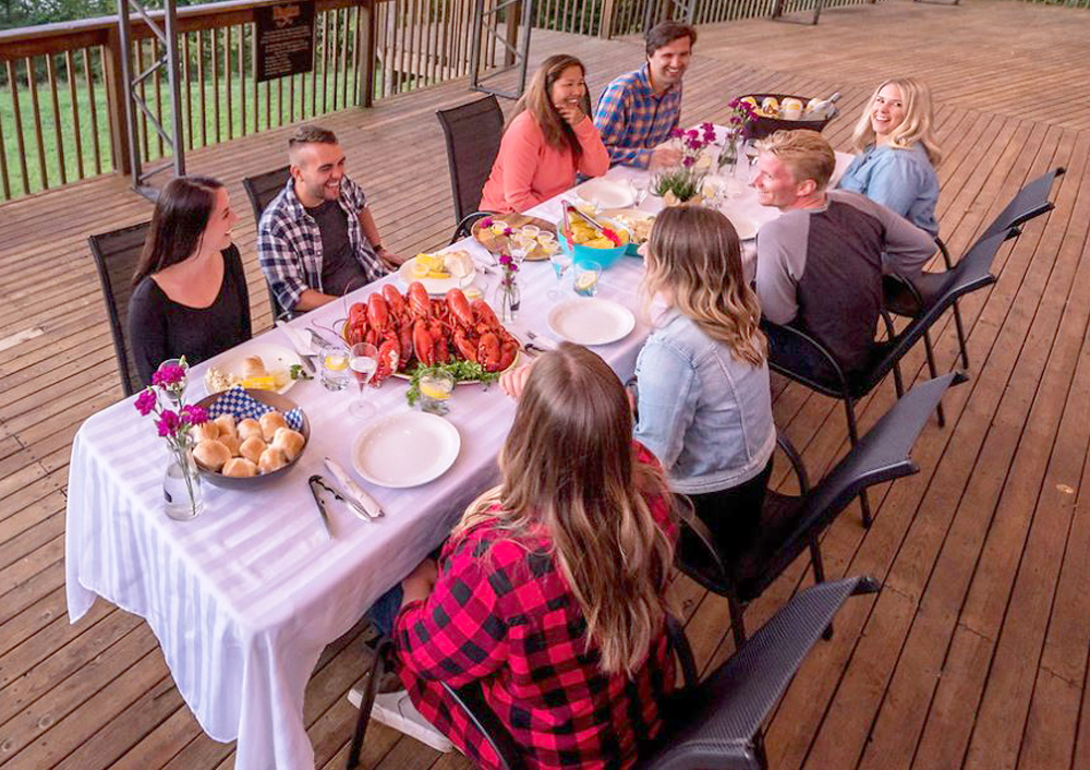 A group of people meeting over a lobster dinner on the large patio at Tidal Bore Rafting Resort in Nova Scotia.